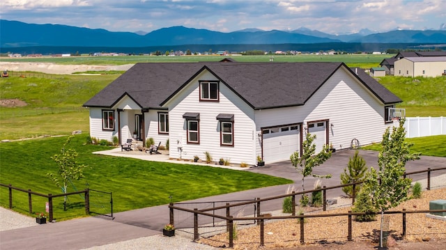 view of front facade with a garage, a mountain view, and a front lawn