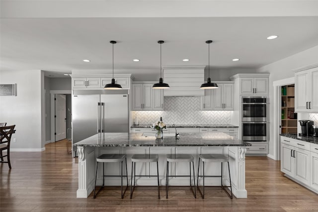 kitchen with decorative light fixtures, a center island with sink, a breakfast bar area, and appliances with stainless steel finishes