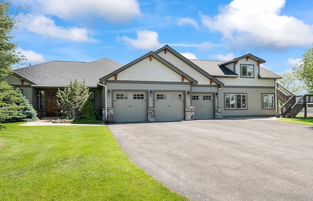 craftsman-style home with a garage, stairway, aphalt driveway, roof with shingles, and a front yard