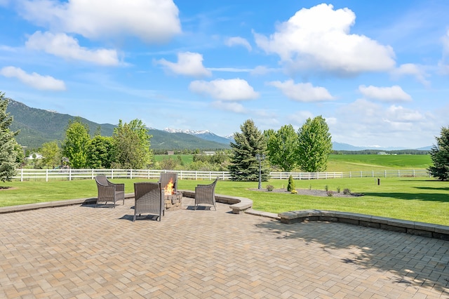 view of patio with an outdoor fire pit, a rural view, and a mountain view