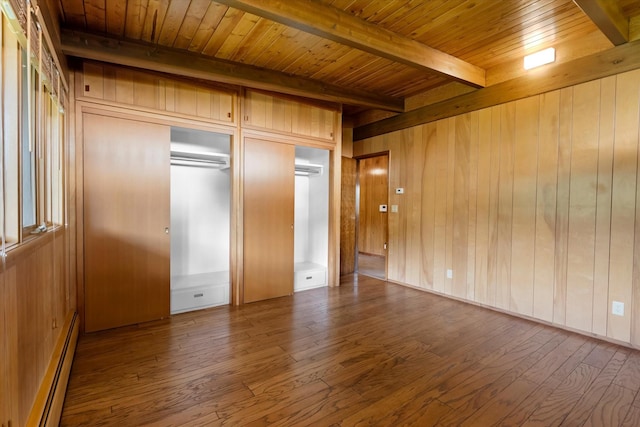 unfurnished bedroom featuring beam ceiling, baseboard heating, and wood finished floors