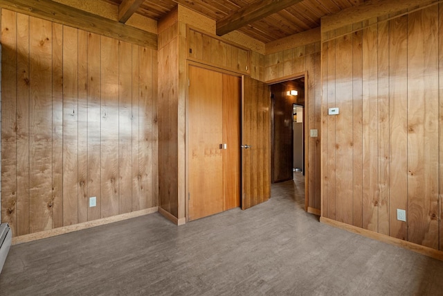 empty room featuring wooden ceiling, wooden walls, wood finished floors, baseboards, and beamed ceiling