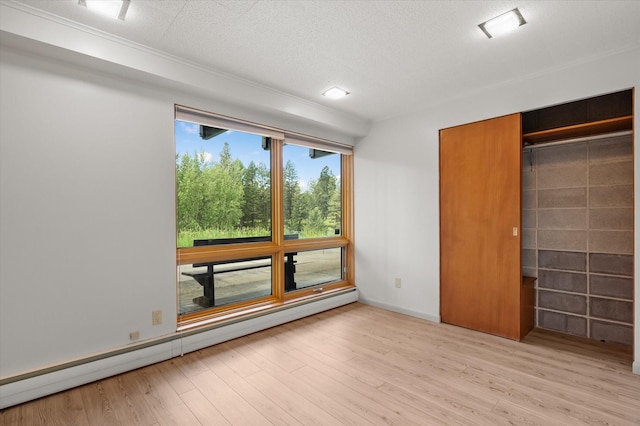 unfurnished bedroom with a textured ceiling, a baseboard heating unit, baseboards, a closet, and light wood-type flooring