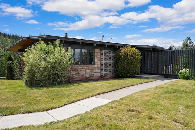 view of property exterior with stone siding and a lawn