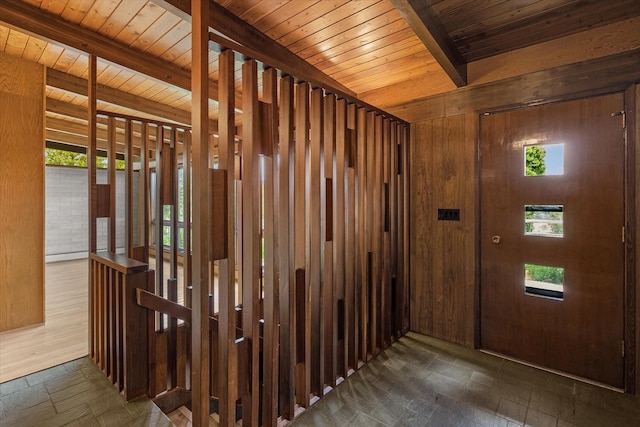 interior space featuring wood ceiling, beam ceiling, wooden walls, and stone tile floors