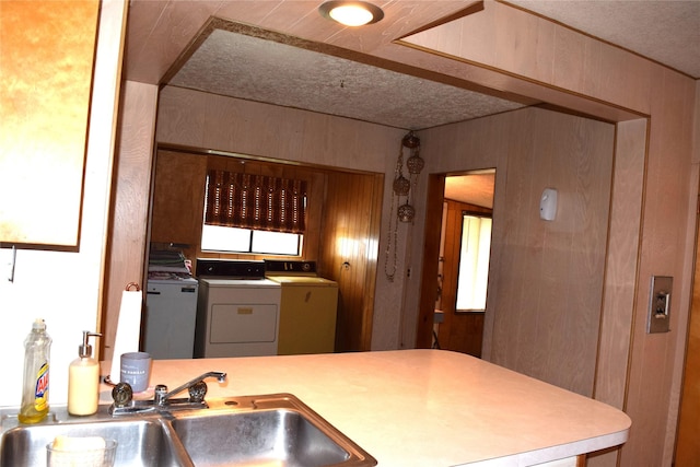 kitchen featuring sink, washing machine and dryer, and wood walls