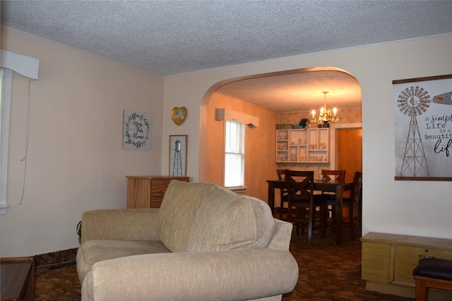 carpeted living room featuring a notable chandelier and a textured ceiling