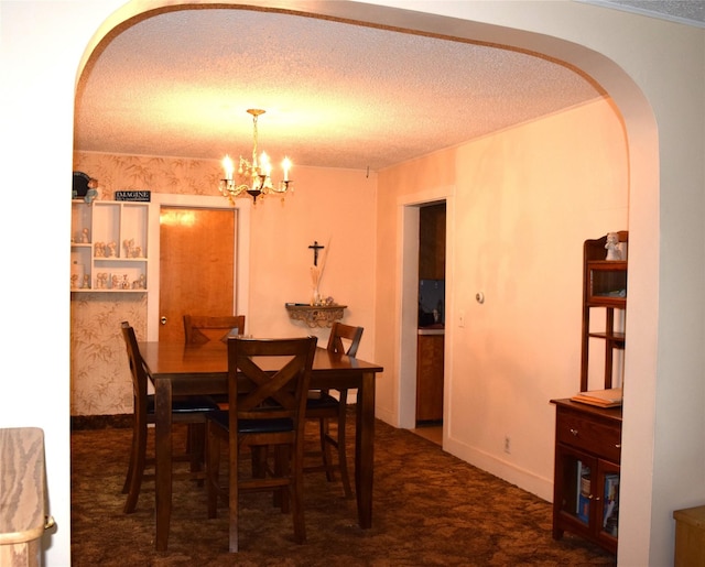 carpeted dining room with an inviting chandelier and a textured ceiling