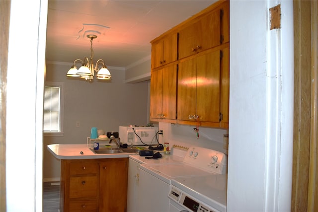 clothes washing area featuring washing machine and dryer, cabinet space, a sink, an inviting chandelier, and ornamental molding