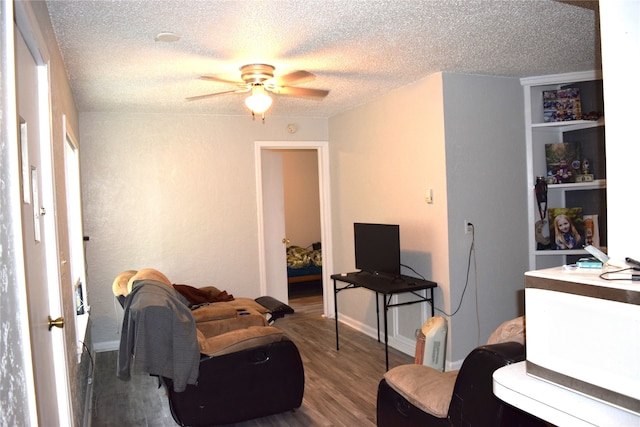 living room featuring a textured ceiling, ceiling fan, and wood finished floors