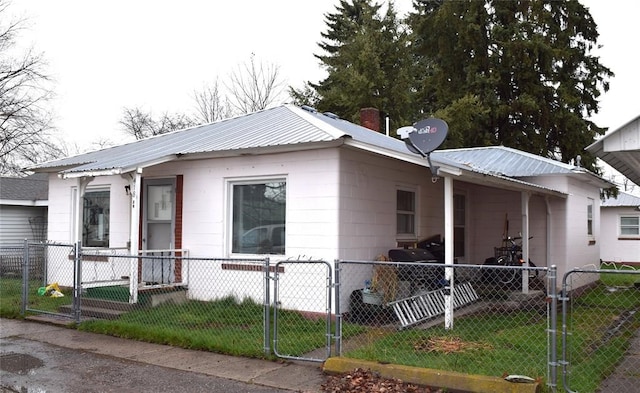 view of home's exterior featuring a lawn, a gate, a fenced front yard, and metal roof
