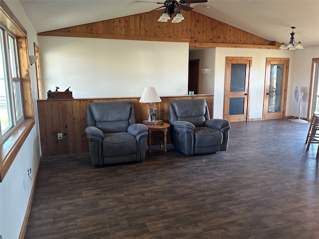 living room with ceiling fan with notable chandelier, wood walls, vaulted ceiling, and dark hardwood / wood-style floors