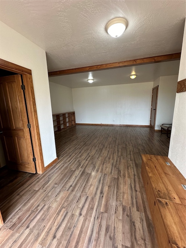 spare room with wood-type flooring, a textured ceiling, and beam ceiling