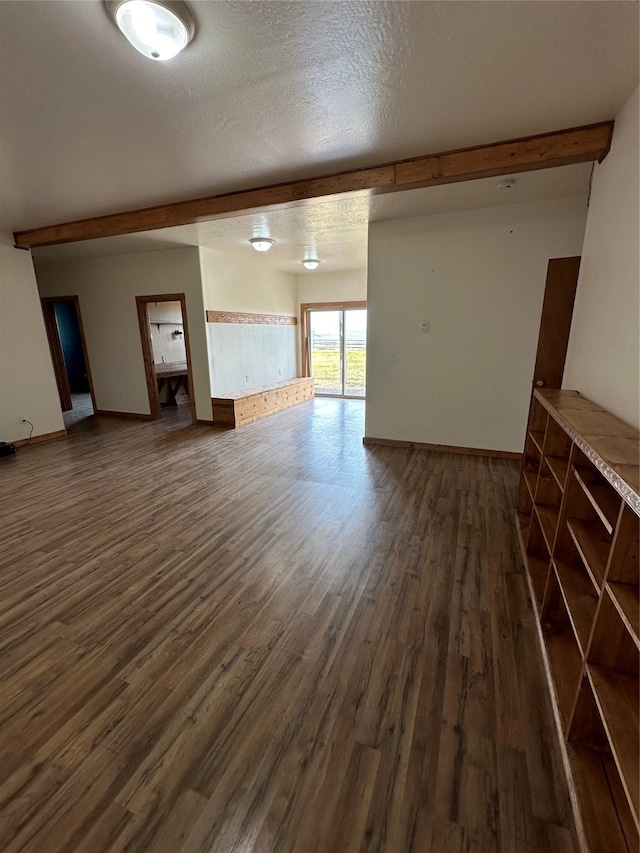 unfurnished living room featuring beamed ceiling, a textured ceiling, and dark wood-type flooring