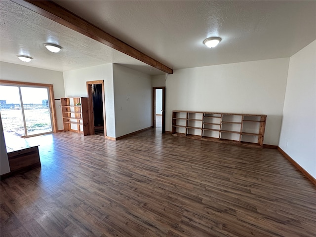 empty room featuring beam ceiling, dark wood-type flooring, and a textured ceiling