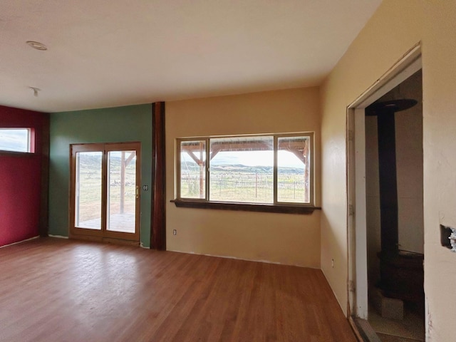 unfurnished room featuring wood-type flooring and a wood stove