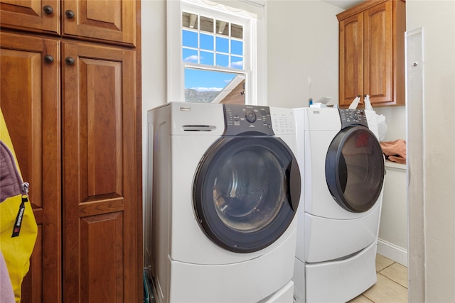 clothes washing area featuring cabinets, light tile patterned floors, and washing machine and dryer