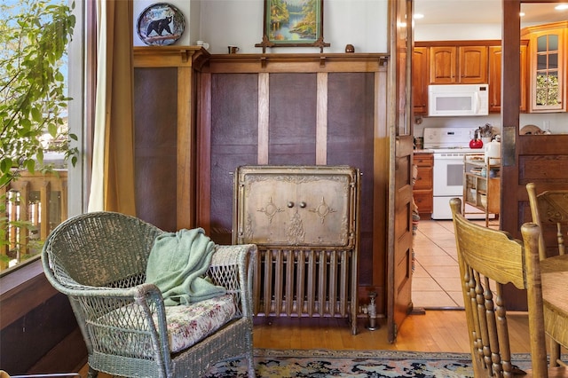 interior space featuring radiator heating unit, white appliances, and light hardwood / wood-style flooring