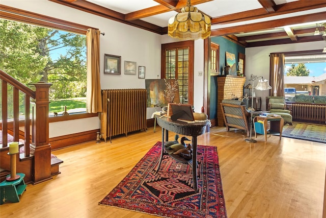 sitting room with radiator heating unit, an inviting chandelier, coffered ceiling, and beam ceiling