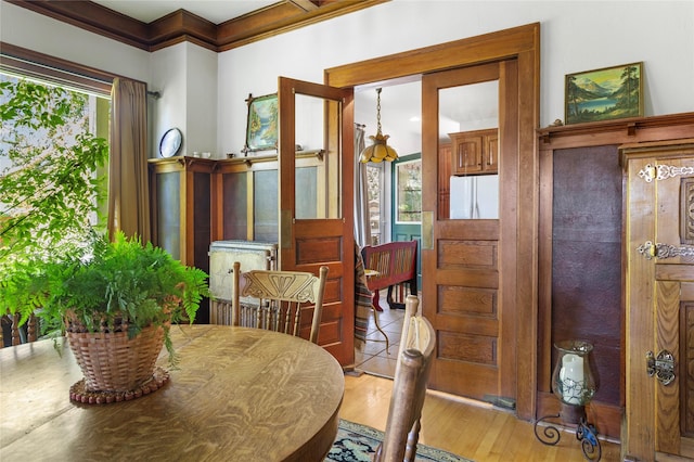 dining area with light wood-type flooring and ornamental molding