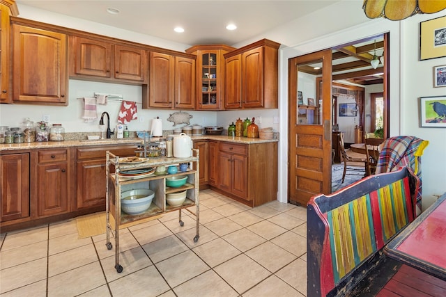 kitchen with light stone counters, light tile patterned floors, and sink