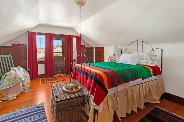 bedroom with hardwood / wood-style floors and lofted ceiling