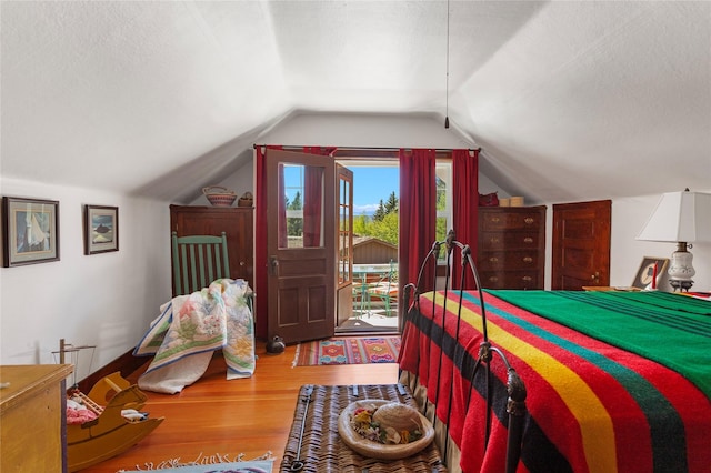 bedroom featuring wood-type flooring, a textured ceiling, and vaulted ceiling