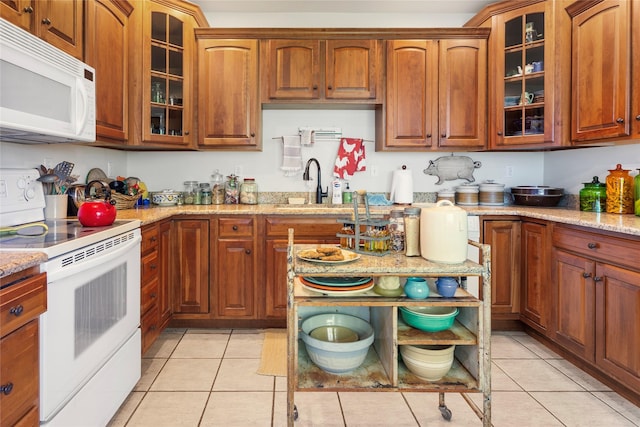 kitchen with light stone countertops, white appliances, sink, and light tile patterned floors