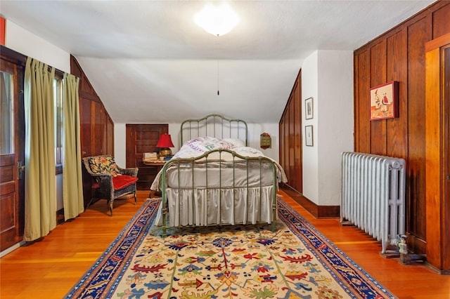 bedroom featuring wood-type flooring, vaulted ceiling, and radiator