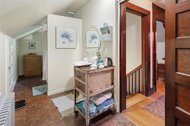 hallway with dark hardwood / wood-style flooring, lofted ceiling, and sink