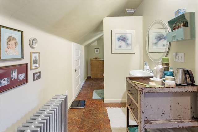 bathroom featuring vanity, lofted ceiling, and radiator