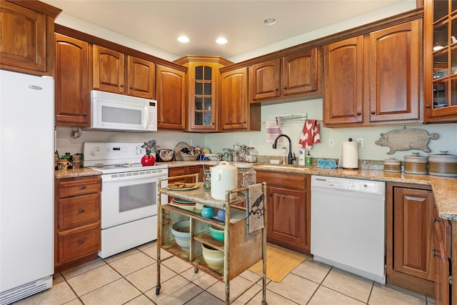 kitchen with light stone counters, white appliances, sink, and light tile patterned floors