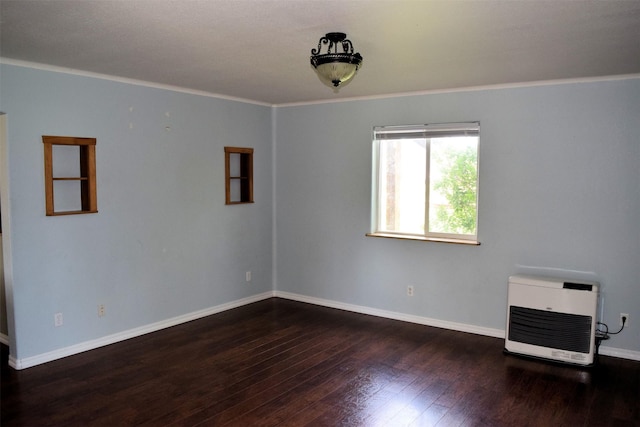 empty room featuring heating unit, dark hardwood / wood-style floors, and crown molding