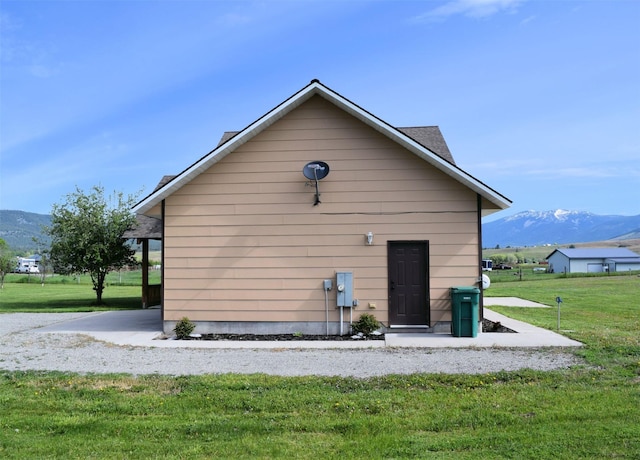 back of property featuring a lawn and a mountain view