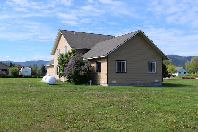 view of property exterior with a mountain view and a lawn