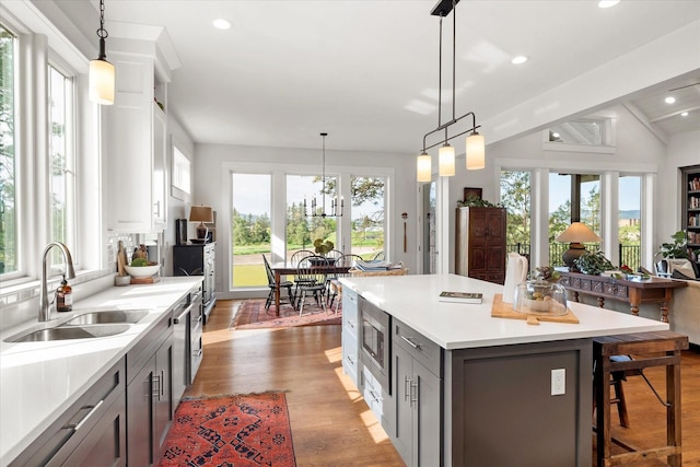 kitchen with sink, decorative light fixtures, gray cabinets, and a center island