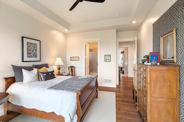 bedroom featuring dark wood-type flooring, ceiling fan, and a tray ceiling