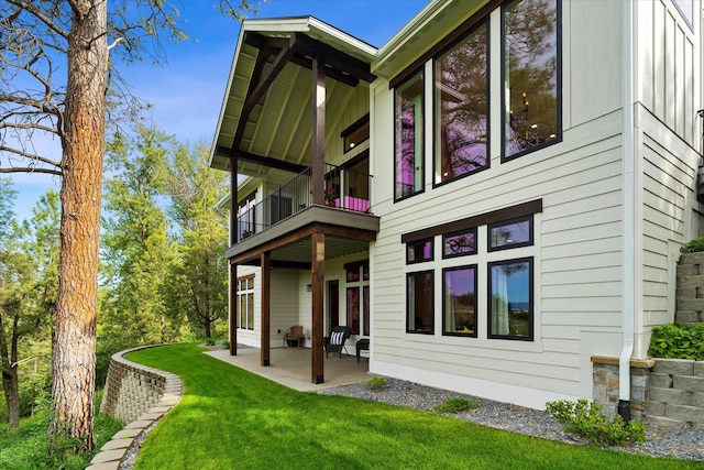 back of house featuring a balcony, a yard, and a patio