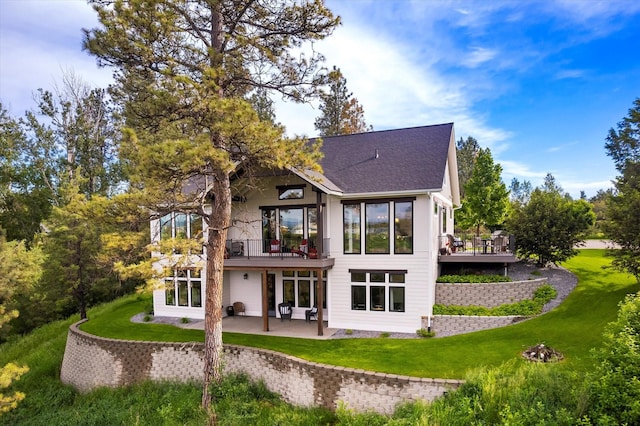 rear view of property with a wooden deck, a lawn, and a patio