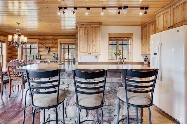 kitchen featuring log walls, a chandelier, white refrigerator with ice dispenser, and rail lighting