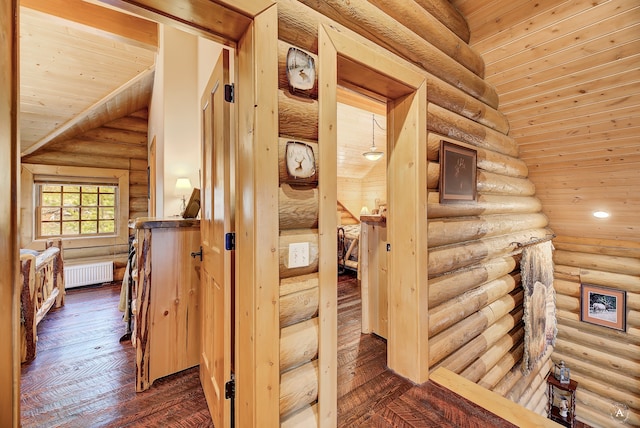 hallway featuring hardwood / wood-style floors, vaulted ceiling, rustic walls, wooden ceiling, and radiator