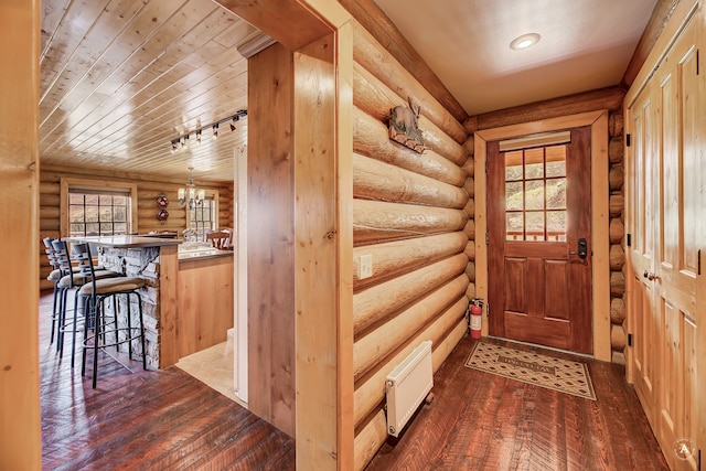 doorway to outside with wooden ceiling, track lighting, dark hardwood / wood-style floors, and log walls