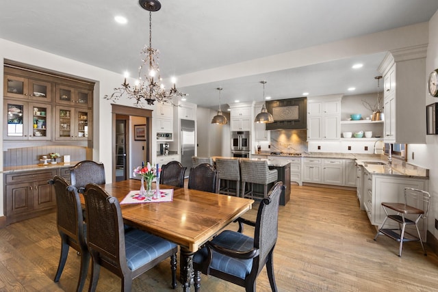 dining area with a chandelier, light hardwood / wood-style floors, and sink