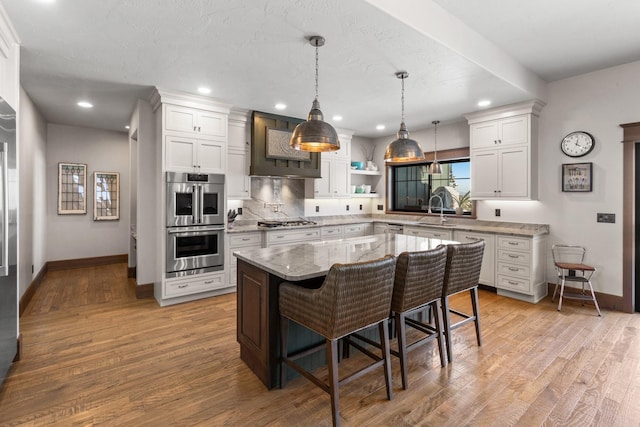 kitchen featuring a breakfast bar, white cabinets, light wood-style floors, appliances with stainless steel finishes, and a center island