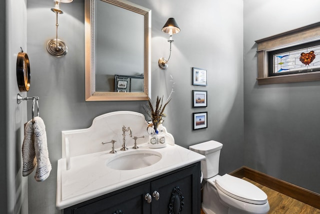 bathroom with toilet, vanity, and baseboards