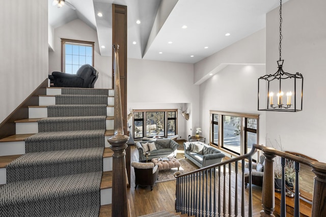 living room featuring stairs, high vaulted ceiling, wood finished floors, and a wealth of natural light