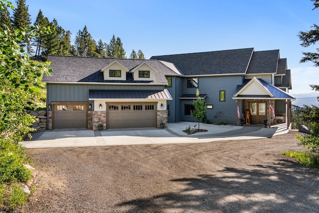 view of front of home featuring driveway, stone siding, a garage, and a standing seam roof