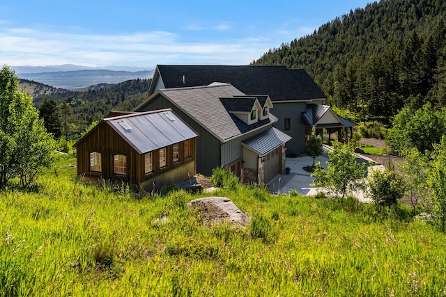 exterior space featuring stone siding, a wooded view, and a mountain view