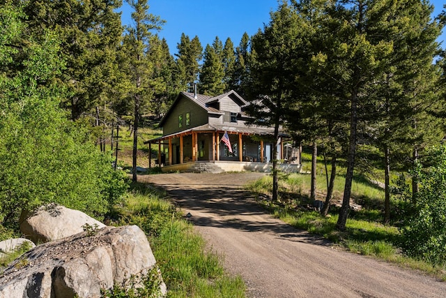 view of front of home featuring dirt driveway and a porch