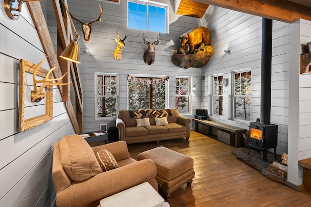 living room with a wood stove, a wealth of natural light, beamed ceiling, and wood-type flooring